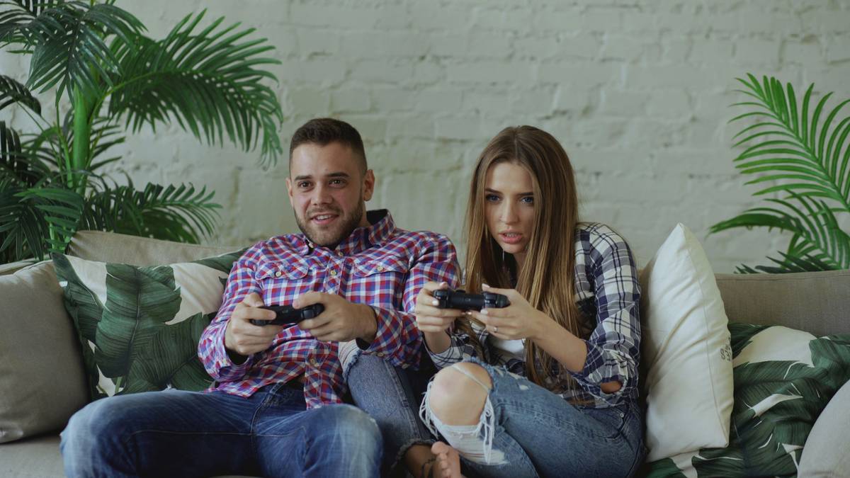 couple playing competitive mobile games for couples on couch with phones